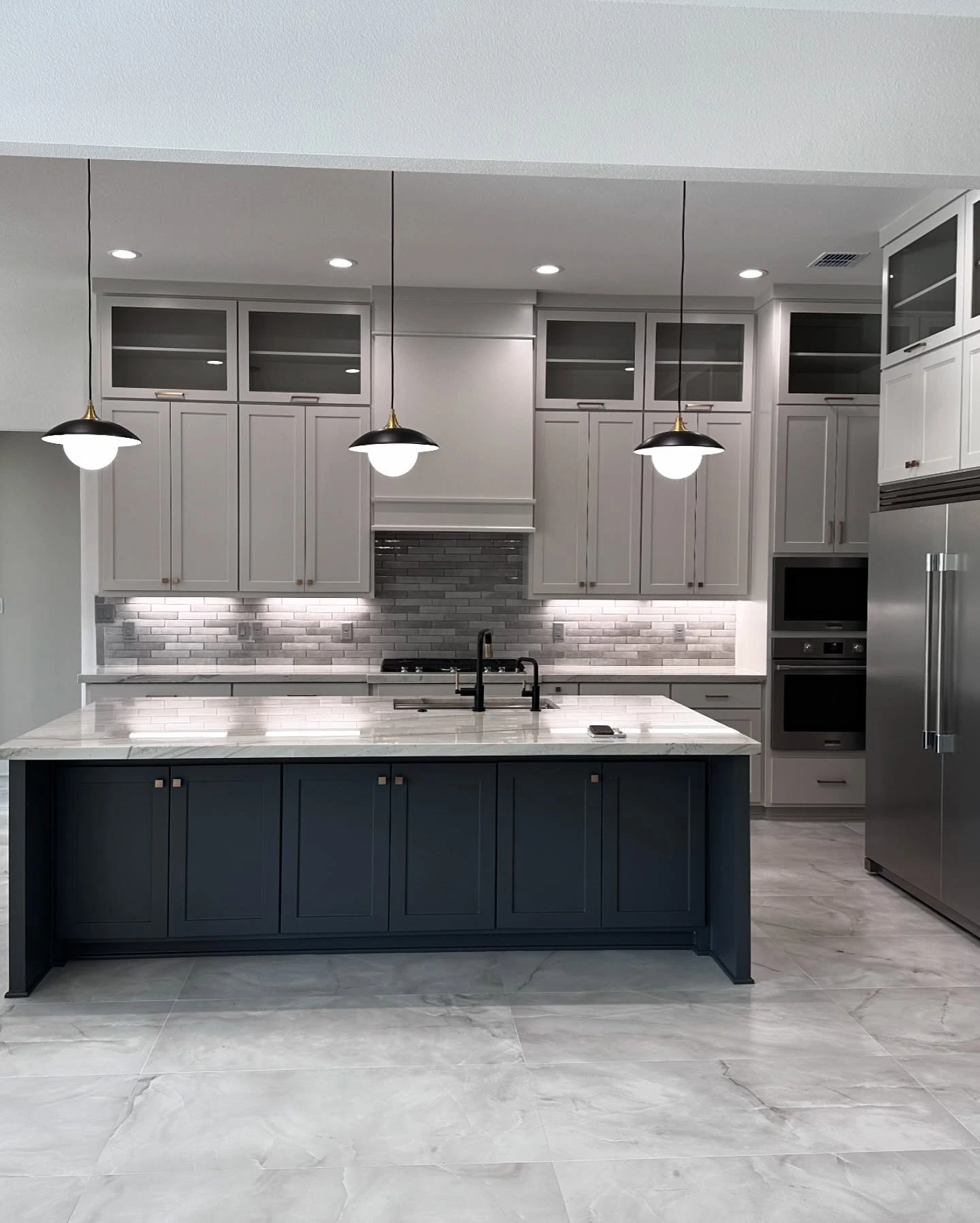 Custom kitchen with navy blue island, marble countertops and pendant lighting, designed by Prince Designs in Tyler, Texas