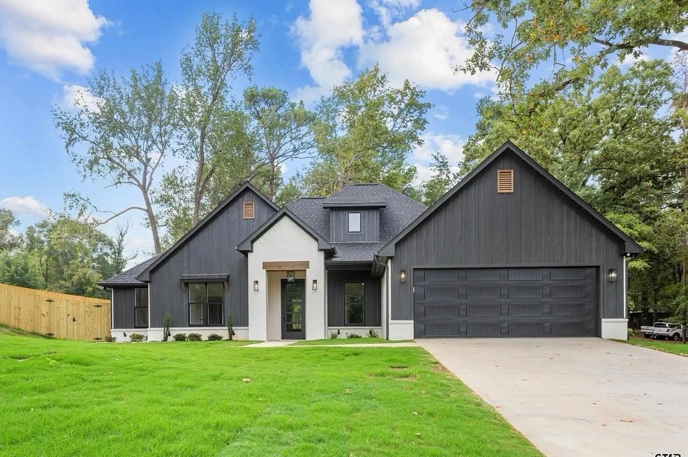 Modern farmhouse home exterior with dark siding, stucco accents, and attached garage built from Prince Designs floor plans